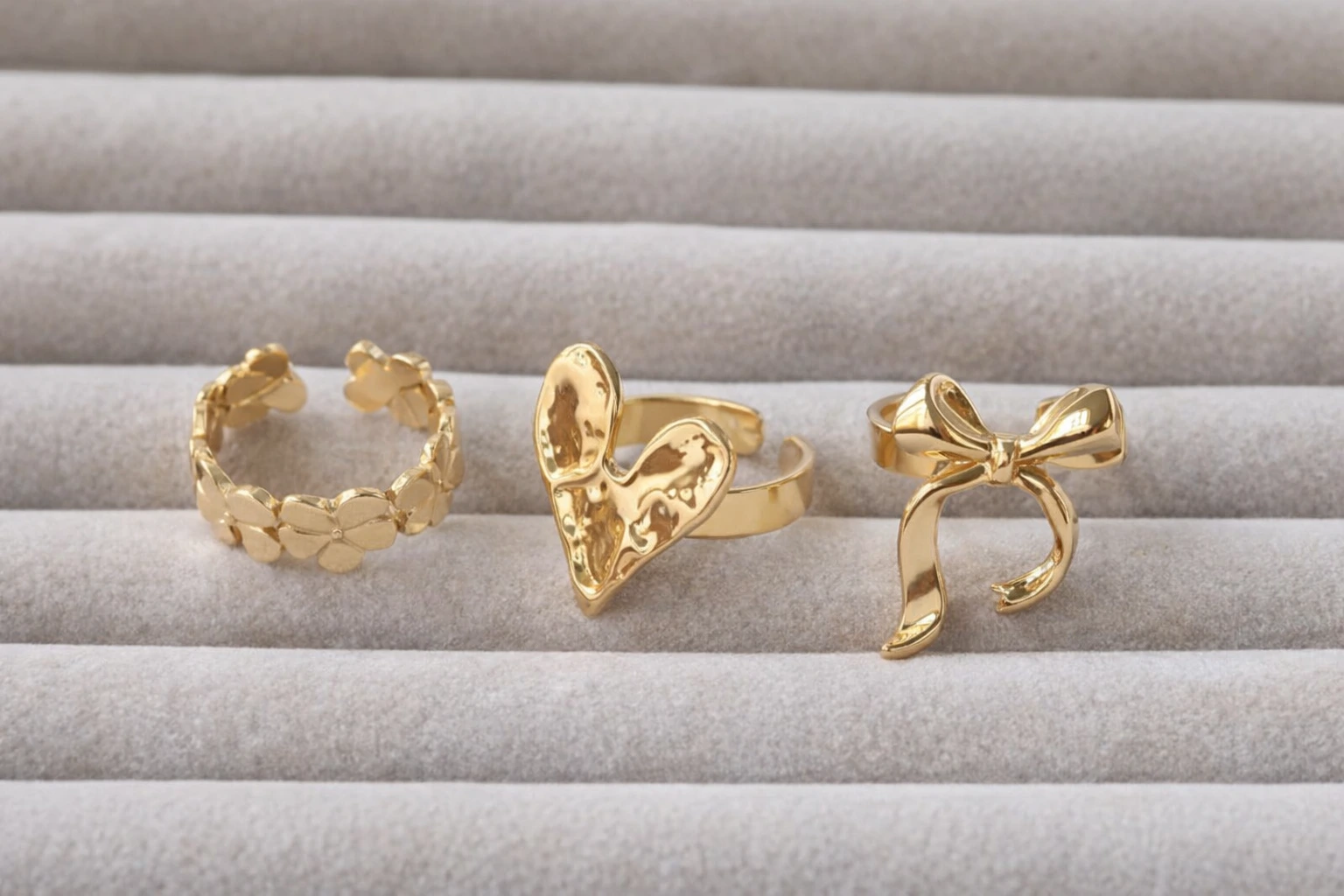 Close up of a woman's hand wearing multiple 18k gold plated rings including an engagement style solitaire.